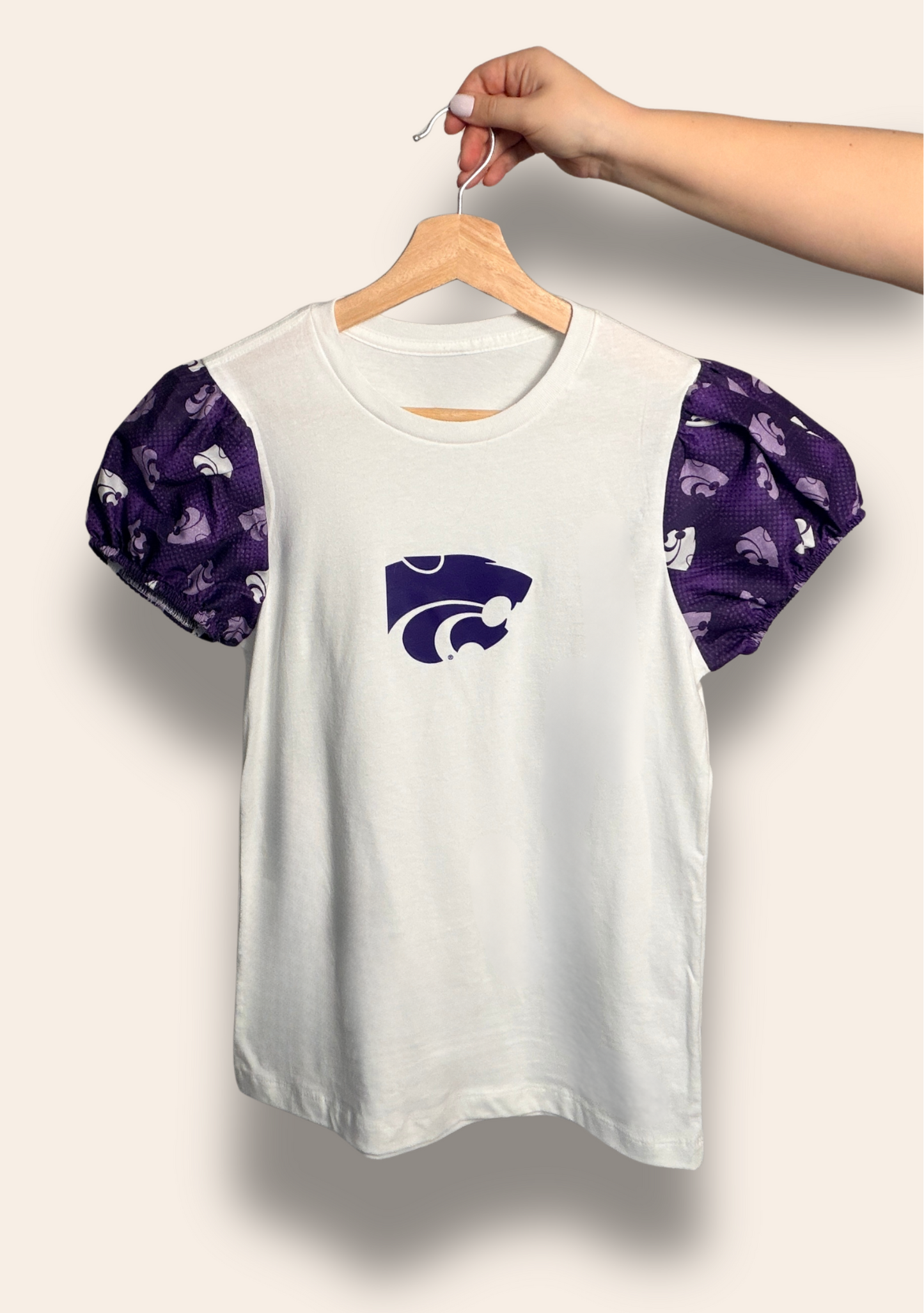 Our K-State Classic Puff Tee features a crisp white body with dreamy purple puff sleeves and the iconic Wildcat front and center. It’s the perfect mix of feminine and fierce, made for tailgates, campus days, and cheering on the Cats in style.
Comfortable, flattering, and guaranteed to get compliments.