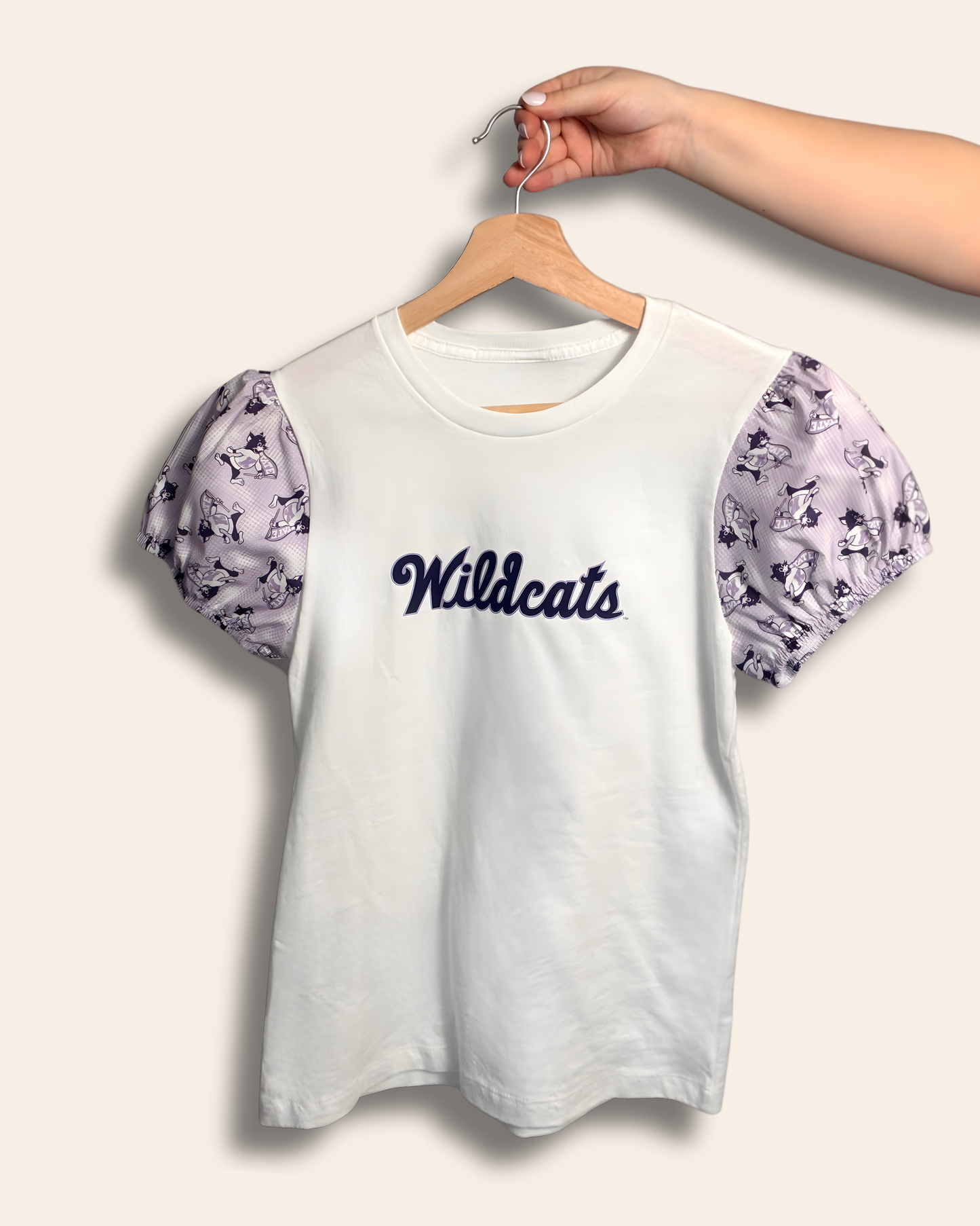 Soft, sweet, and full of Wildcat pride.
Our Wildcats Script Puff Tee features delicate lavender puff sleeves with playful Wildcat details and a classic script front that feels timeless and feminine. It’s the perfect elevated game day look for cheering on K-State, strolling campus, or repping your Wildcats wherever you go.
Comfortable, flattering, and made for the cutest fan in purple.