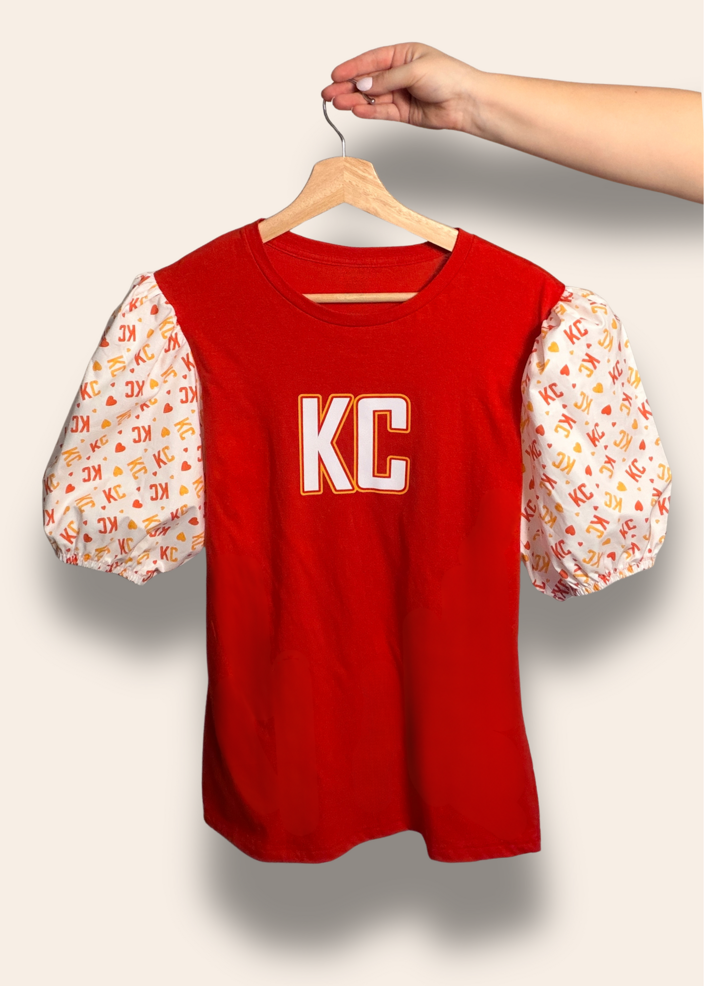 For the girls who cheer loud and dress cute doing it.
Our Red Kingdom Sweetheart Puff Tee features a bold red base with dreamy puff sleeves covered in KC and heart details for the perfect mix of sporty and feminine. It’s made for tailgates, touchdowns, and every Kansas City win in between.
Comfortable, flattering, and guaranteed to turn heads on game day.