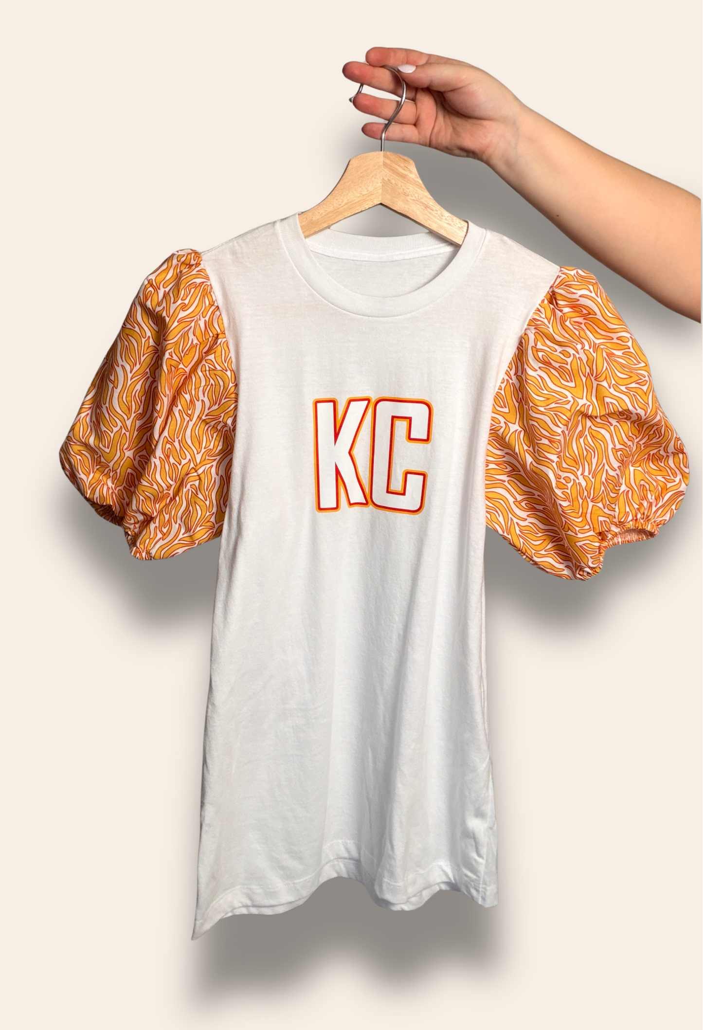 For the girls who belong to the Kingdom.

Our KC Kingdom Puff Tee features a classic white base with bold KC lettering and statement puff sleeves in vibrant red and gold tones. Feminine, bold, and made for game day, it’s the perfect top for tailgates, touchdowns, and cheering on Kansas City in style.

Comfortable, flattering, and made to stand out in a sea of red.