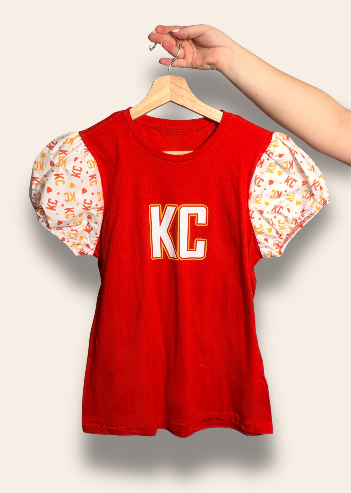 For the girls who cheer loud and dress cute doing it.

Our Red Kingdom Sweetheart Puff Tee features a bold red base with dreamy puff sleeves covered in KC and heart details for the perfect mix of sporty and feminine. It’s made for tailgates, touchdowns, and every Kansas City win in between.

Comfortable, flattering, and guaranteed to turn heads on game day.